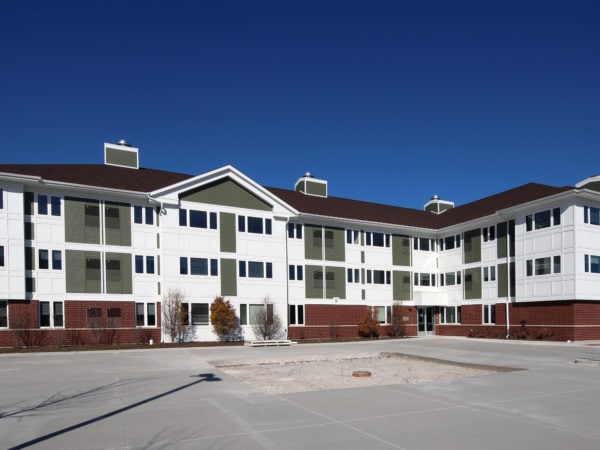 Three story apartment building with white, green and red brick facade.