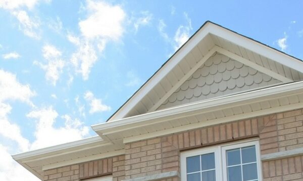 Roofline of a home with light tan brick and white trim.