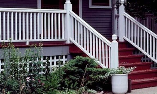 Front steps and porch of a house with white railings, red steps, and plants.