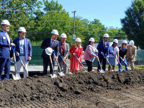 People in hard hats smiling with shovels