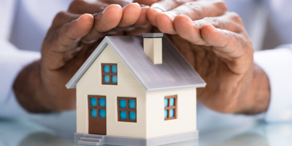 Close-up,Of,A,Person's,Hand,Protecting,Miniature,House,On,The