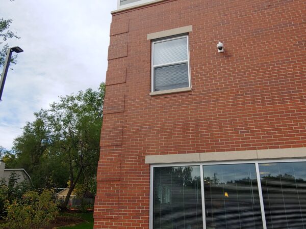 Three story apartment building with red brick and light blue-grey siding.