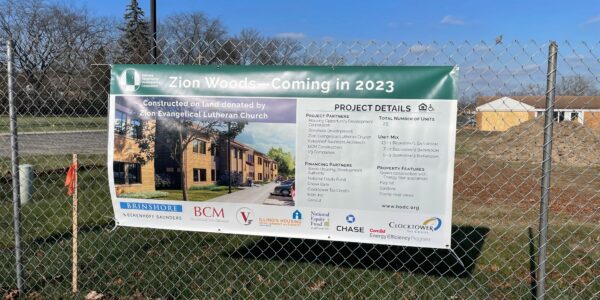 Large construction banner affixed to a chain link construction fence.
