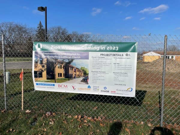 Large construction banner affixed to a chain link construction fence.