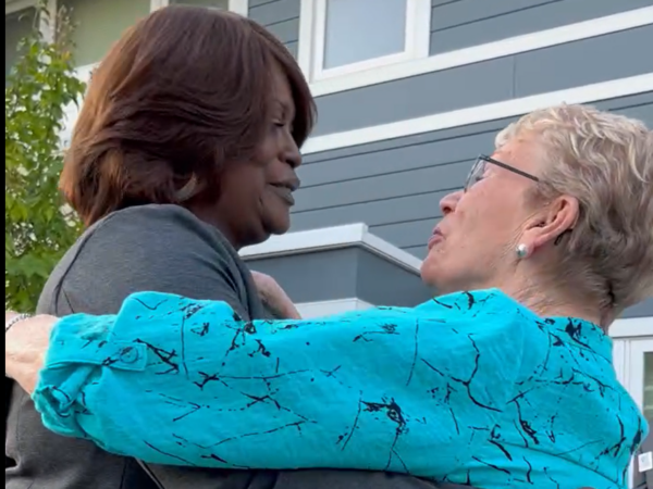 Two women embrace. The mood is caring and supportive.