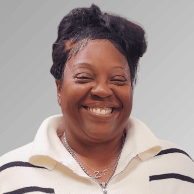 Smiling black woman wearing a white sweater with black stripes and a necklace.