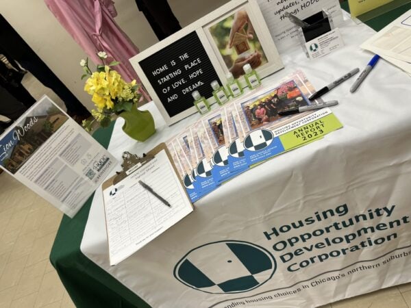A table with a table runner with the HODC logo and various paperwork.