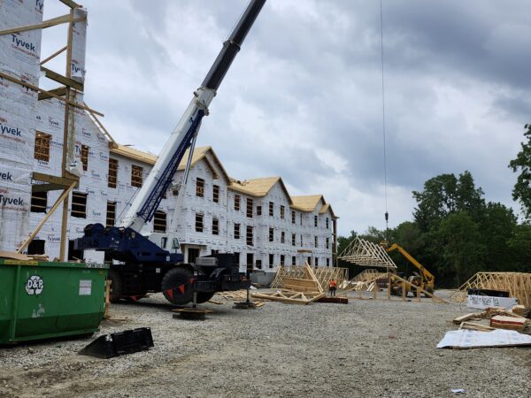 A crane and other construction items are in front of a three story building under construction.