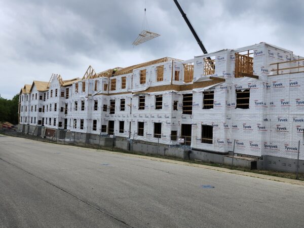 A three story building under construction. A crane towers above.