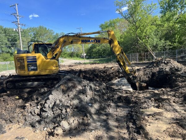 A small construction vehicle digs in the ground.