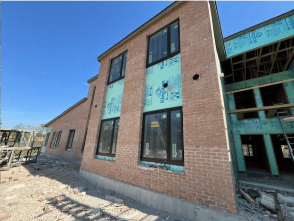 A construction site of a two-story apartment building with light brown brick.