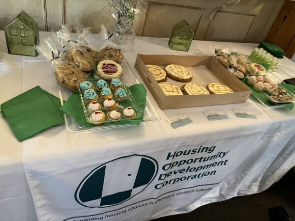 A table setting with various sweets, and a table runner with the HODC logo.
