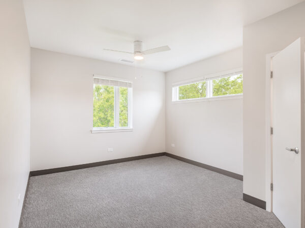 Bedroom with no furniture, white walls and grey carpet.