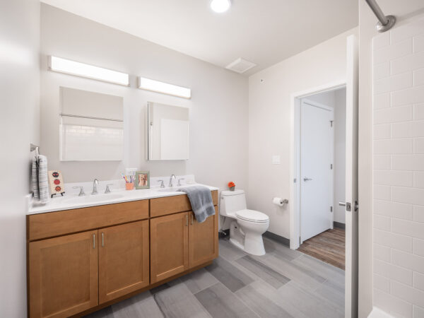Bathroom with two sinks, a white toilet and oak cabinets.