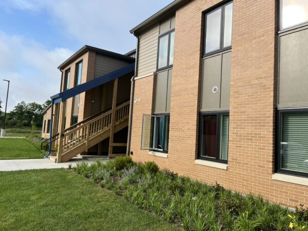 Two story apartment building. Wooden stairs go to the second floor. Stairs are covered by blue metal covering.