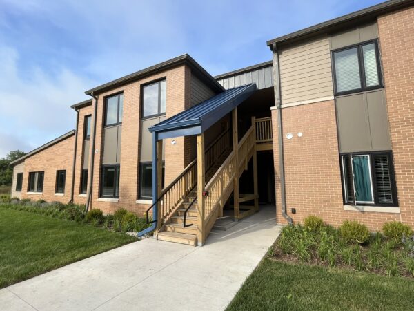 Two story apartment building. Wooden stairs go to the second floor. Stairs are covered by blue metal covering.
