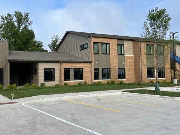 Two story apartment building with parking lot and green grass.