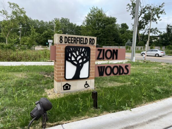 Zion Woods building sign with green grass and trees.