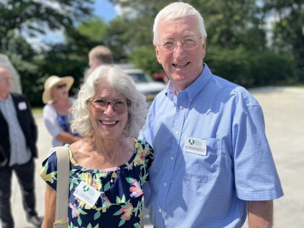 A man and woman pose together outside. The mood is sunny and upbeat.
