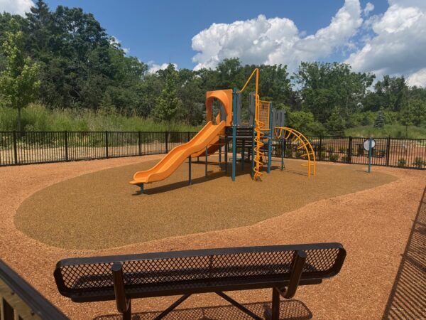 A black bench faces a children's playbround.