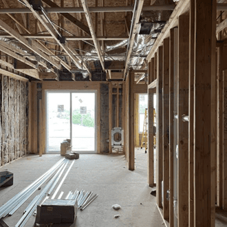 The interior of an apartment under construction with partially finished walls and construction equipment.