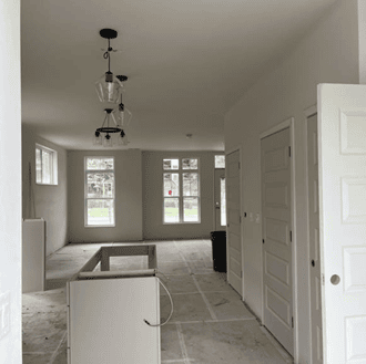 An interior of an apartment is under construction. Cabinets are partially installed and the subfloor is ready for flooring.