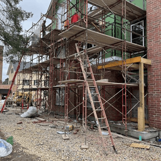 Workers are on a scaffolding that is next to a building under construction.