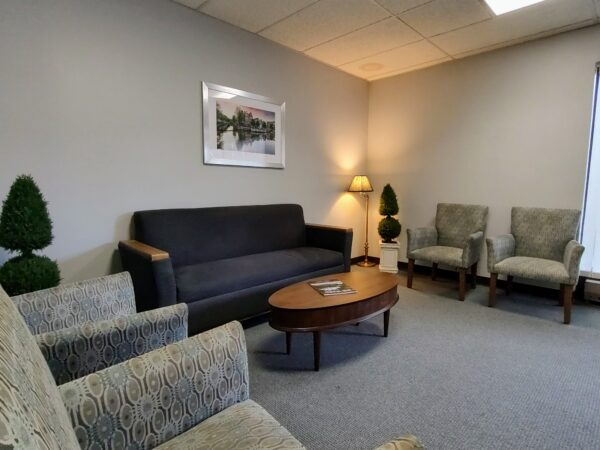 A sitting room with large comfortable chairs, a couch, a coffee table and soft lighting and decor.