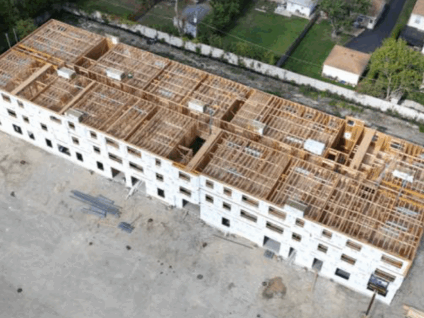 Construction site of a four-story apartment building with an unfinished roof and siding.