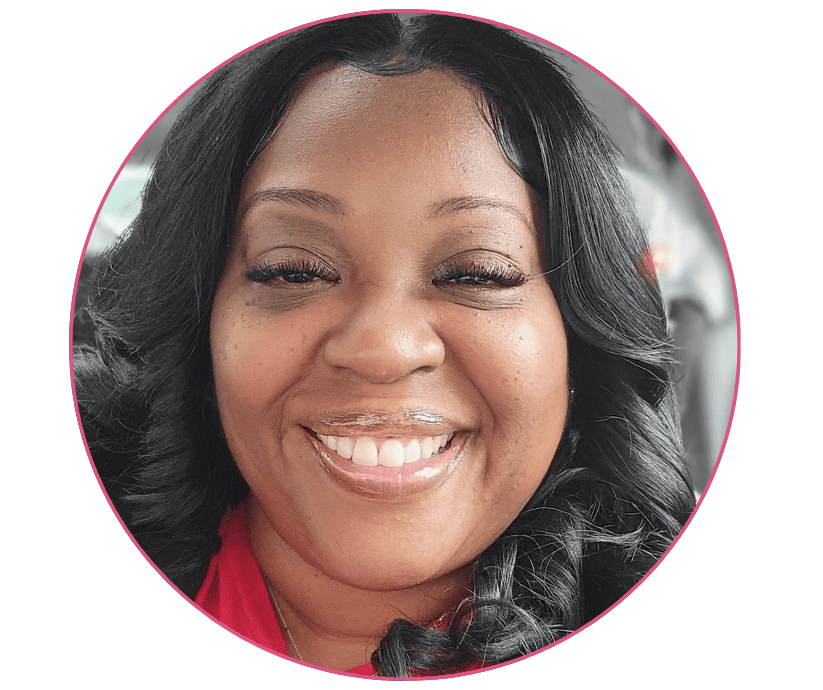 A woman with curly black hair smiles warmly at the camera, wearing a red top. The background shows a car interior, conveying a cheerful tone.