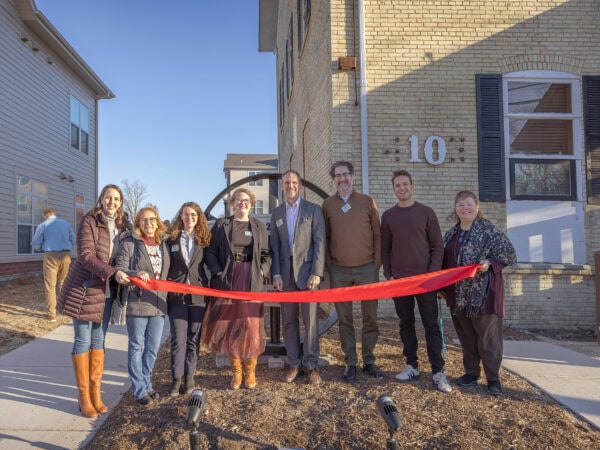 HODC community members at ribbon-cutting event outside building.