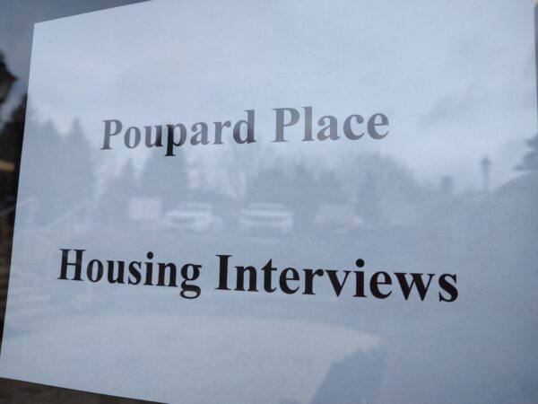 "Poupard Place Housing Interviews" in black letters on white paper posted in a glass window.